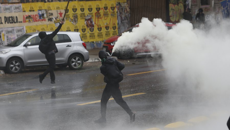Desórdenes registrados en la Alameda dejan a tres detenidos: encapuchados quemaron una bandera de Chile